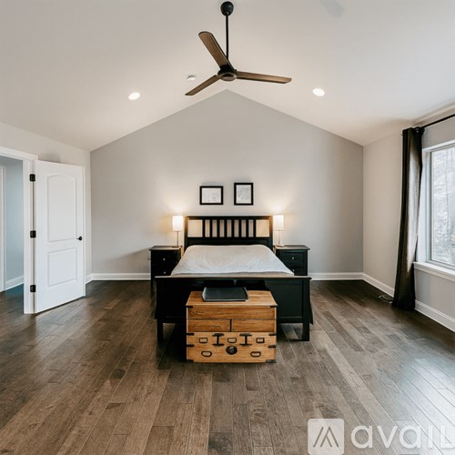 A bedroom with a bed, dresser, and ceiling fan.