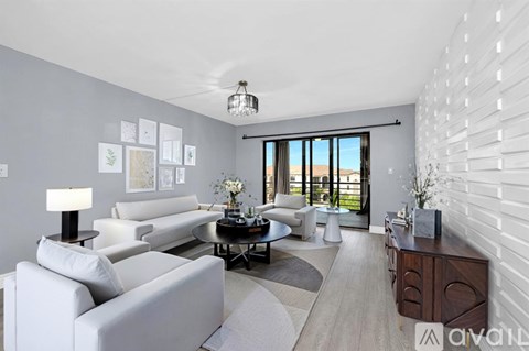 A living room with white furniture and a large window.