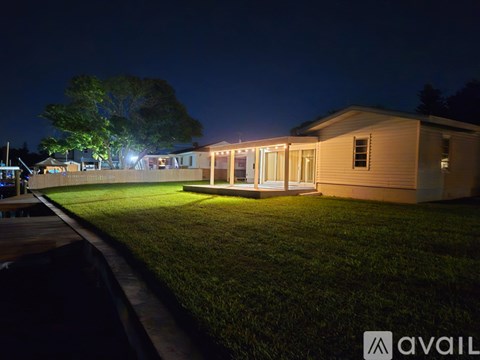 A house is lit up at night with a grassy front yard.