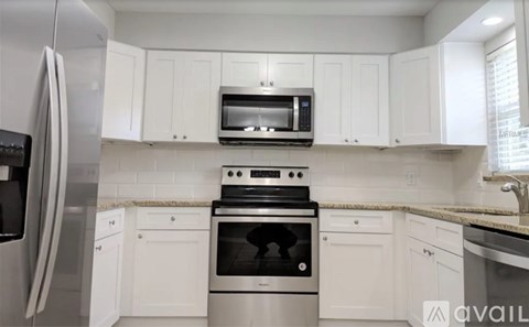 A kitchen with white cabinets and a stainless steel refrigerator.