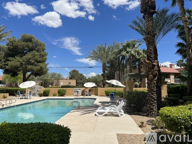A pool surrounded by palm trees and patio furniture.