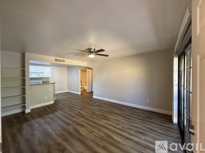 A spacious room with a ceiling fan and wooden flooring.
