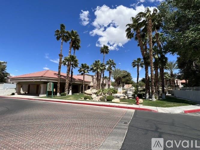 A building with a red roof is surrounded by palm trees.
