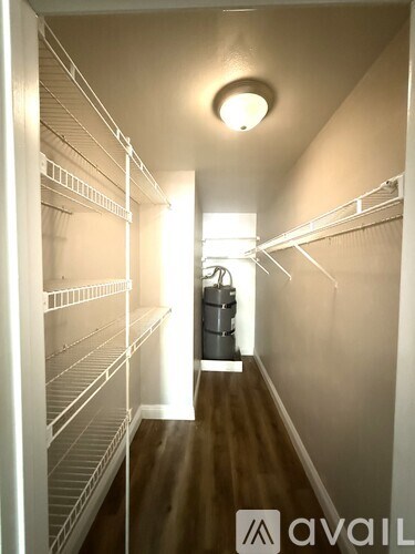 A long hallway with a light on the ceiling and a trash can in the middle.