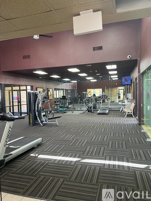 A gym with a variety of equipment including treadmills and weights.