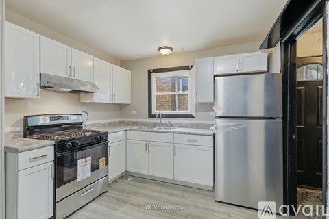 A kitchen with white cabinets and a stainless steel refrigerator.