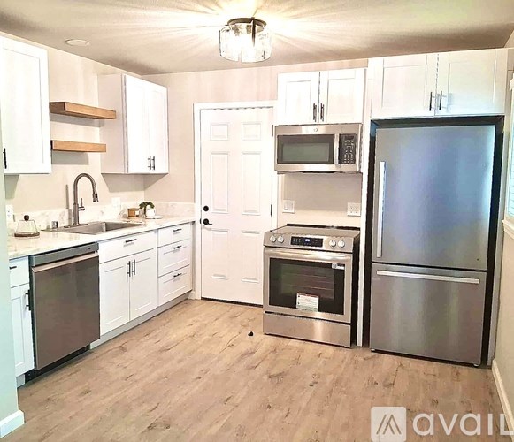 A kitchen with white cabinets and a wooden shelf above the sink.