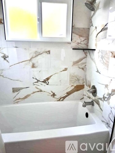 A bathroom with a marble patterned wall and a white sink.