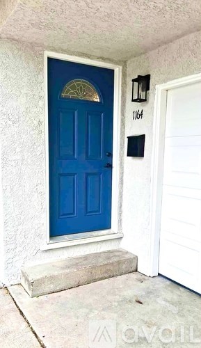A blue door with a gold design in the middle and a black mailbox with the number 1164 on it.