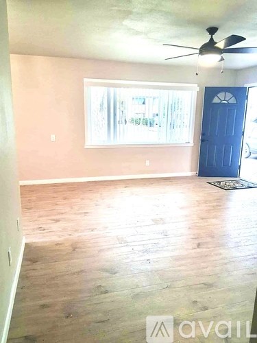 A room with a ceiling fan and a large window.