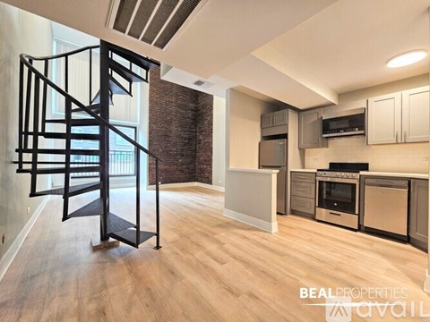 A modern kitchen with a spiral staircase on the left side.
