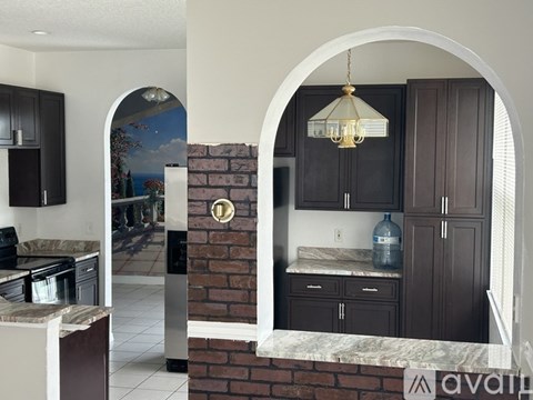 A kitchen with dark brown cabinets and a brick wall.