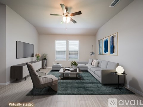 A living room with a grey sofa, a brown chair, a coffee table, a flat screen TV, and a painting on the wall.