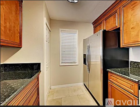 A kitchen with wooden cabinets and a black refrigerator.
