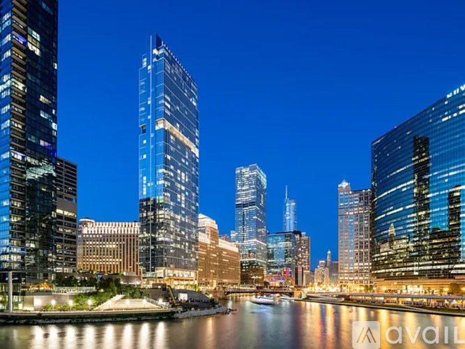 A cityscape at dusk with buildings reflecting on the water.