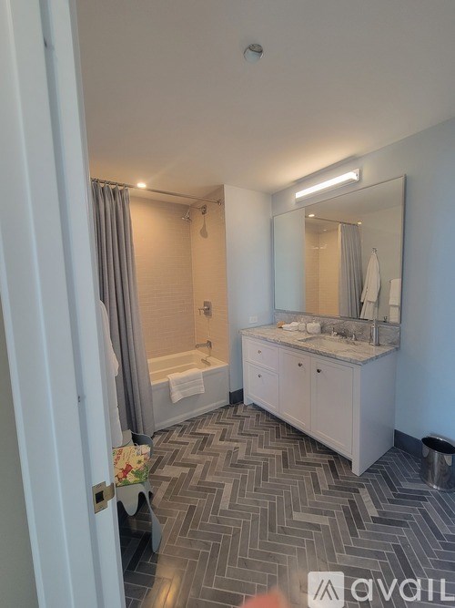 A bathroom with a large mirror, sink, and bathtub.