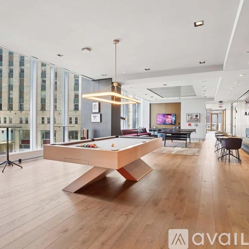 A pool table is in the middle of a room with a high ceiling and large windows.