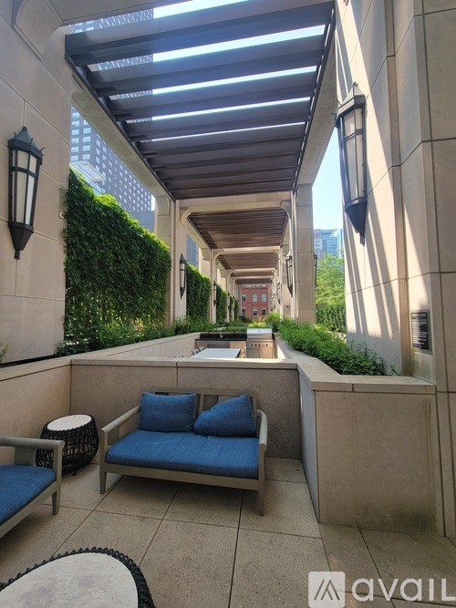 A patio with a blue cushioned bench and a table with a lamp on the side.