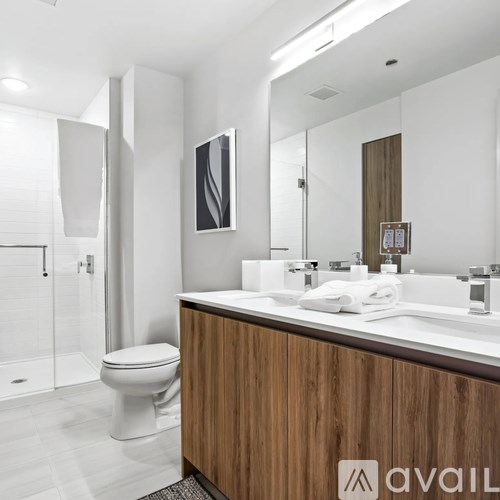A bathroom with a toilet, sink, mirror and a wooden cabinet.