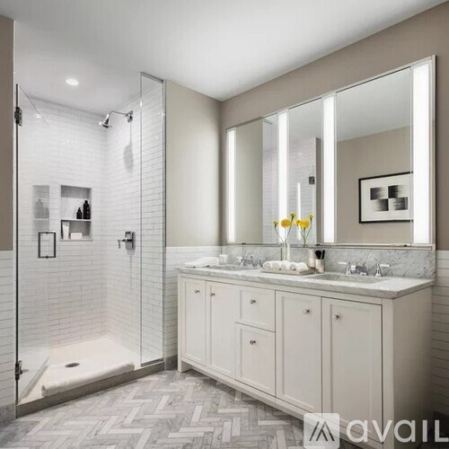 A bathroom with a walk-in shower and double sinks.