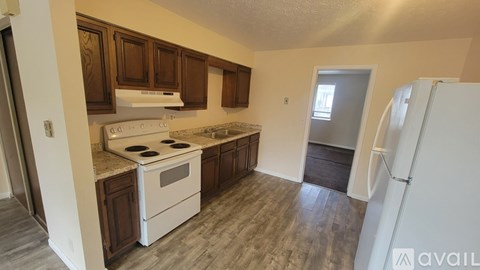 A kitchen with white appliances and wooden cabinets.