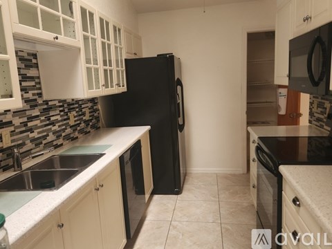 A kitchen with black appliances and white cabinets.