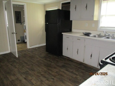 A kitchen with a black fridge and white cabinets.