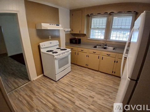 A kitchen with a white stove and wooden floors.