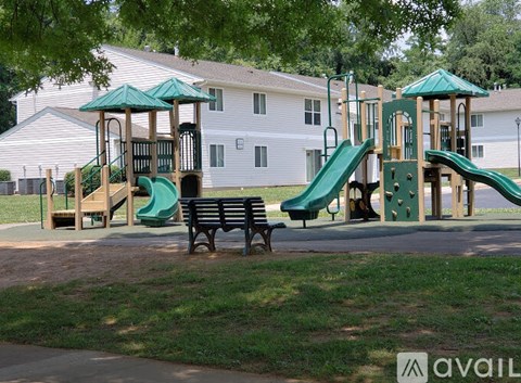 A playground with a green slide and a wooden structure.