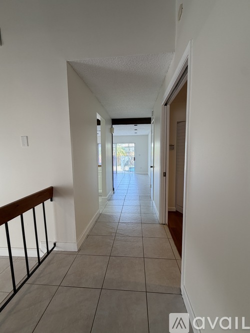 A long hallway with tiled floors and white walls.