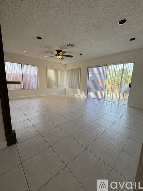 A spacious room with a ceiling fan and large windows.