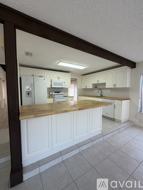 A kitchen with white cabinets and a wooden island.