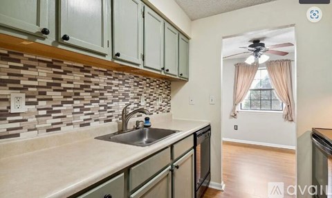 A kitchen with a tile backsplash and a window with curtains.