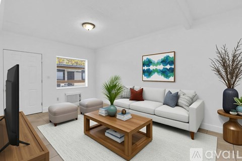 A living room with a white couch, a wooden coffee table, and a painting on the wall.