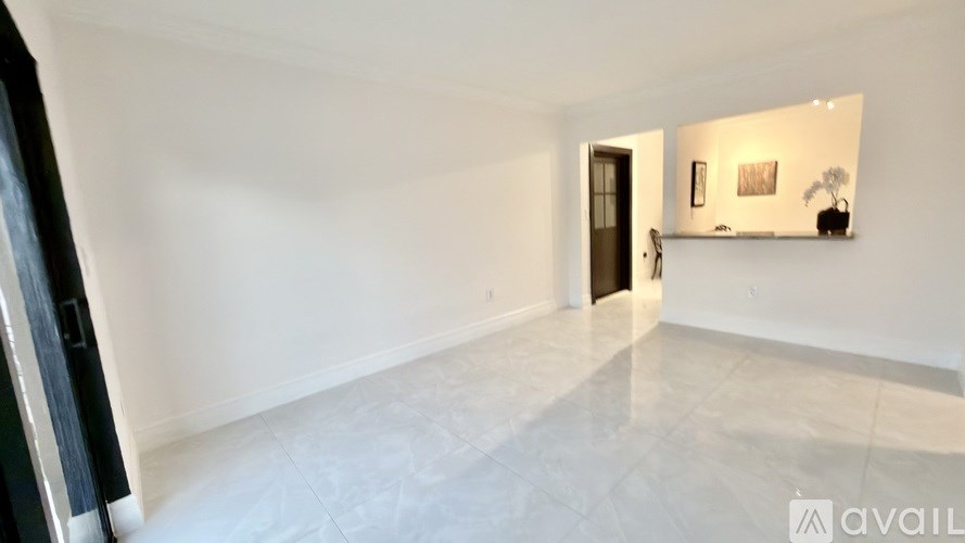 A palm tree stands in front of a house with a stone pillar.