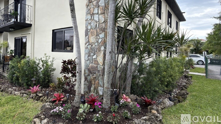A white house with a stone pillar and a garden in front.