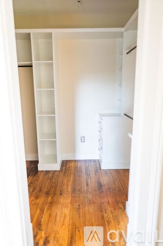 A white refrigerator in a kitchen with wooden floors.