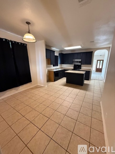 A kitchen with black cabinets and a tiled floor.
