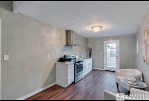 A kitchen with a stove top oven and a dining table with chairs.