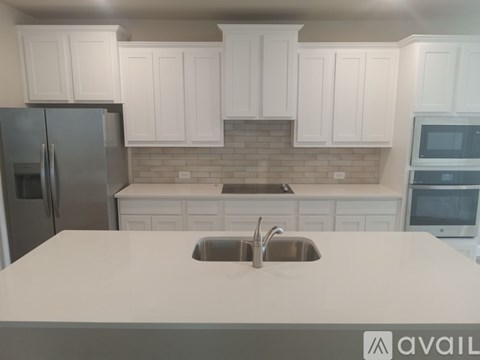 A kitchen with white cabinets and a refrigerator.