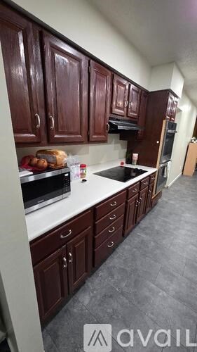 A kitchen with dark wood cabinets and white countertops.
