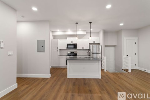A modern kitchen with white cabinets and a wooden floor.