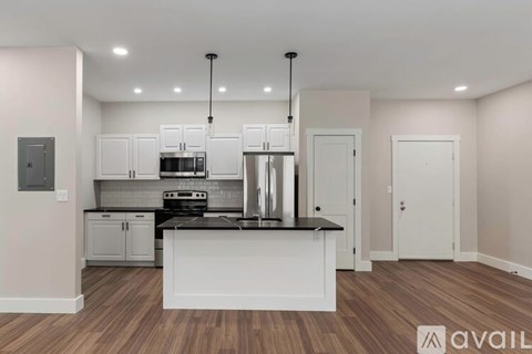 A modern kitchen with white cabinets and a wooden floor.