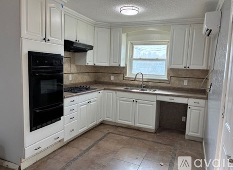 A kitchen with white cabinets and a black oven.