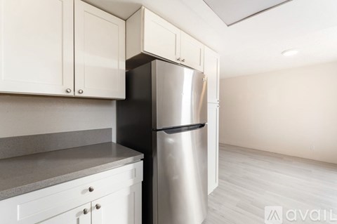 A kitchen with a stainless steel refrigerator and white cabinets.