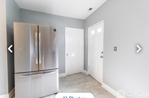 A kitchen with a stainless steel refrigerator and white cabinets.