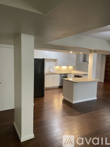 A kitchen with white cabinets and a black refrigerator.