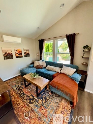 A living room with a blue couch and a rug.