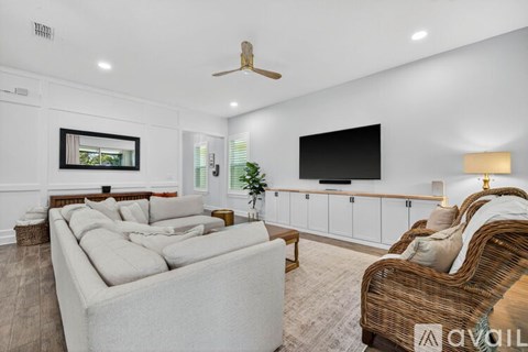 A living room with a white couch and a television on the wall.