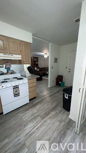 A kitchen with a white stove top oven and wooden cabinets.